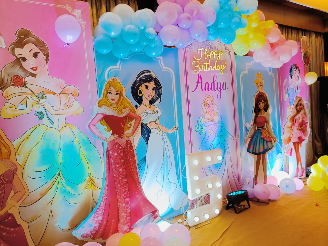 Decorative setup with princess cutouts and balloons for a birthday party.
