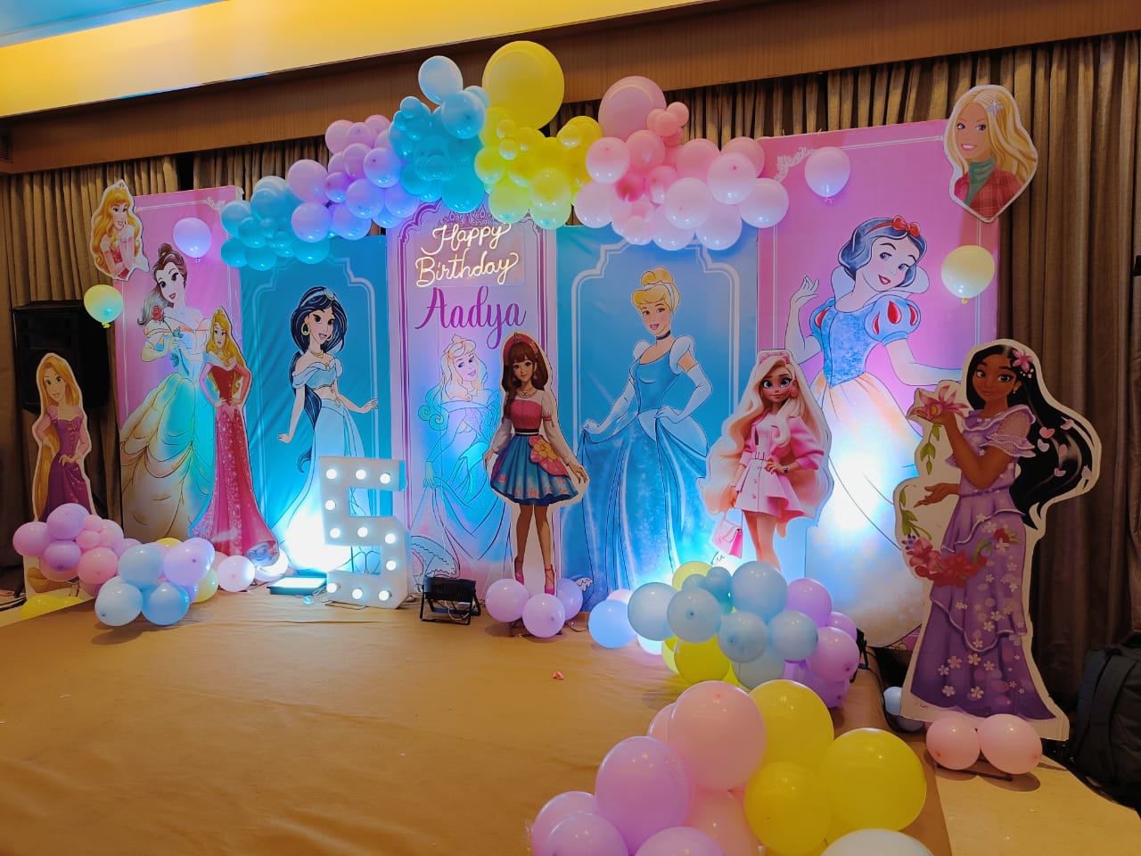 Decorative setup with princess cutouts and balloons for a birthday party.